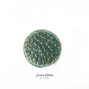 A green and gold round button with the words " stardust collection by paula."