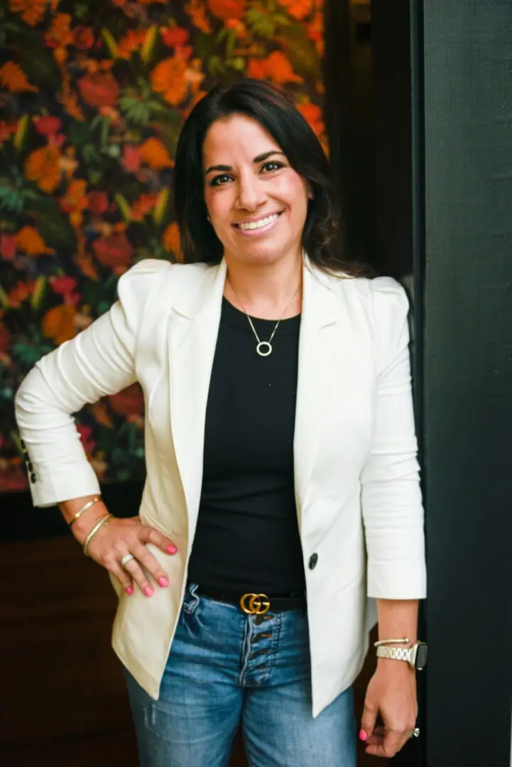 A woman in white jacket standing next to wall.