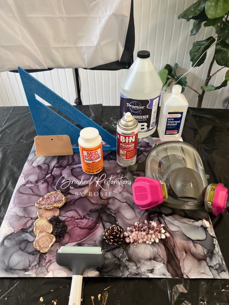 Detailed view of a resin art setup with various supplies including primer, resin, and safety equipment on a marbled workspace.