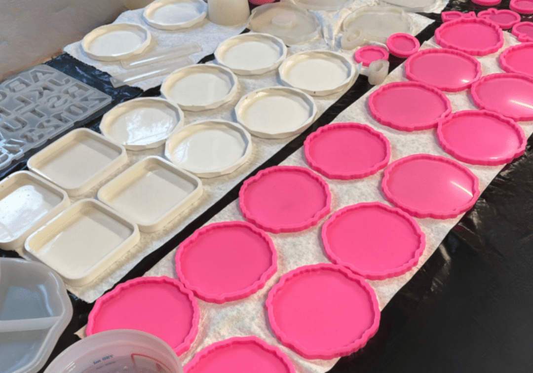 Variety of custom silicone resin molds in pink and white for crafting coasters, trays, and decorative pieces by Brushed Restorations